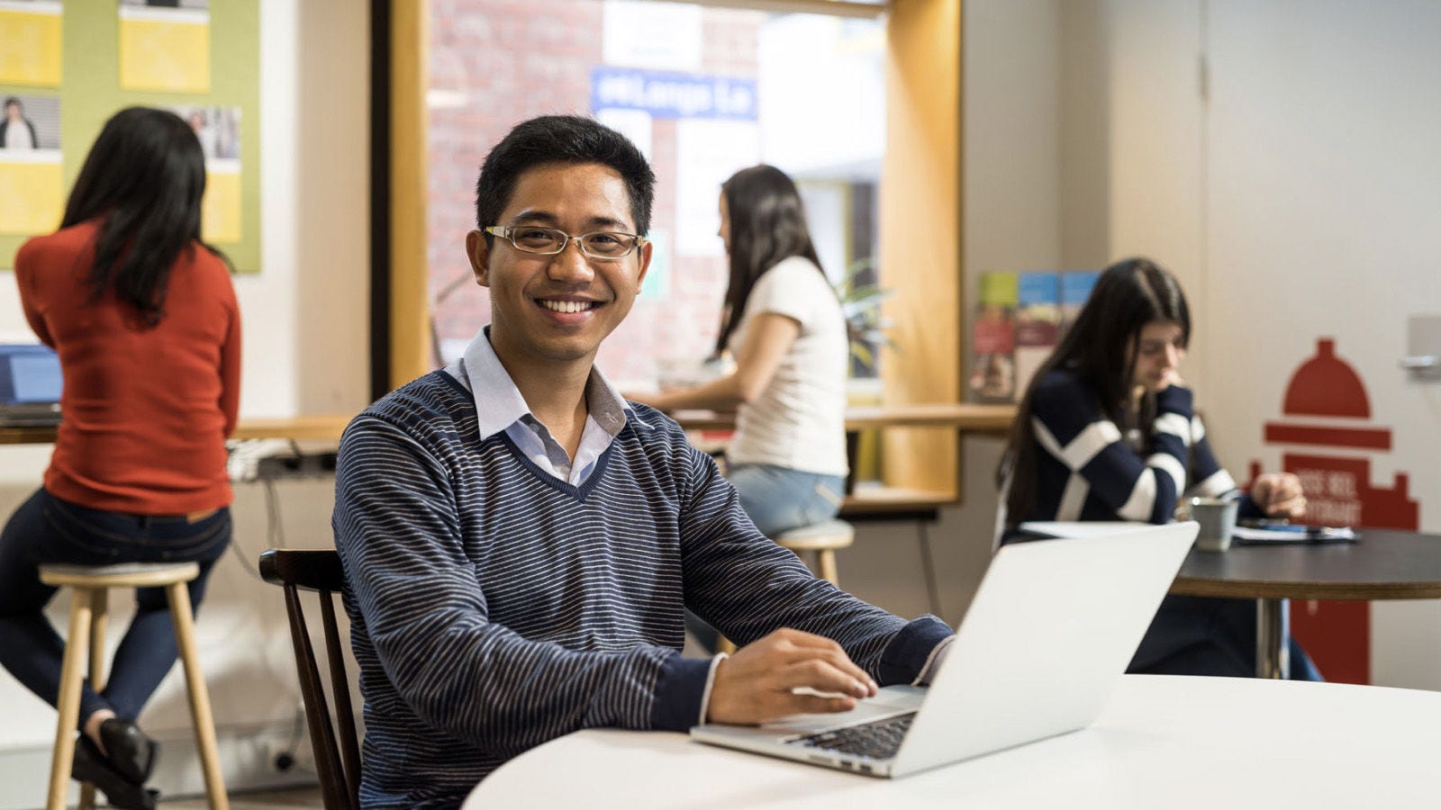 책상에 앉아 컴퓨터를 하면서 웃고 있는 학생.