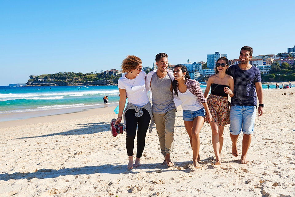 Um grupo de estudantes internacionais aproveitando um dia em Bondi Beach, Sydney. Imagem de cortesia da Destination NSW