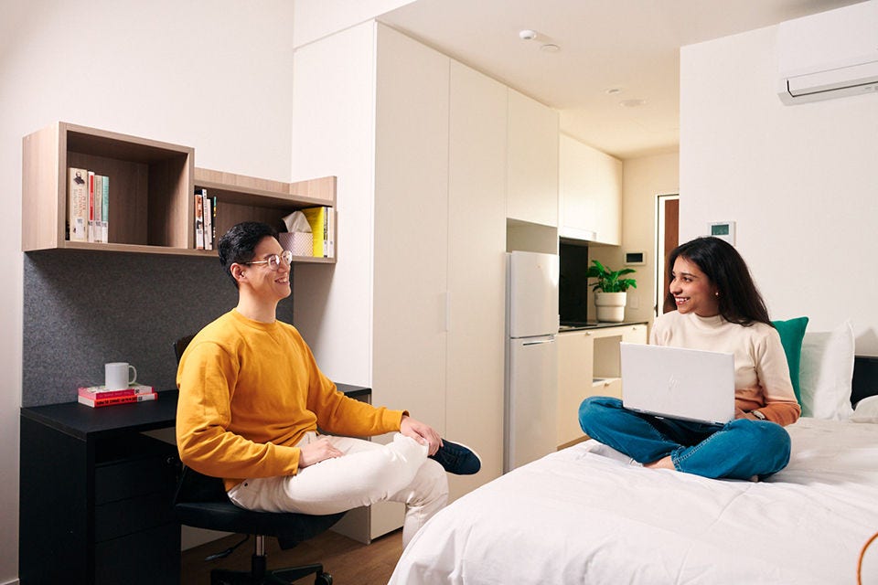 Two international students sit having a conversation in a university accommodation room