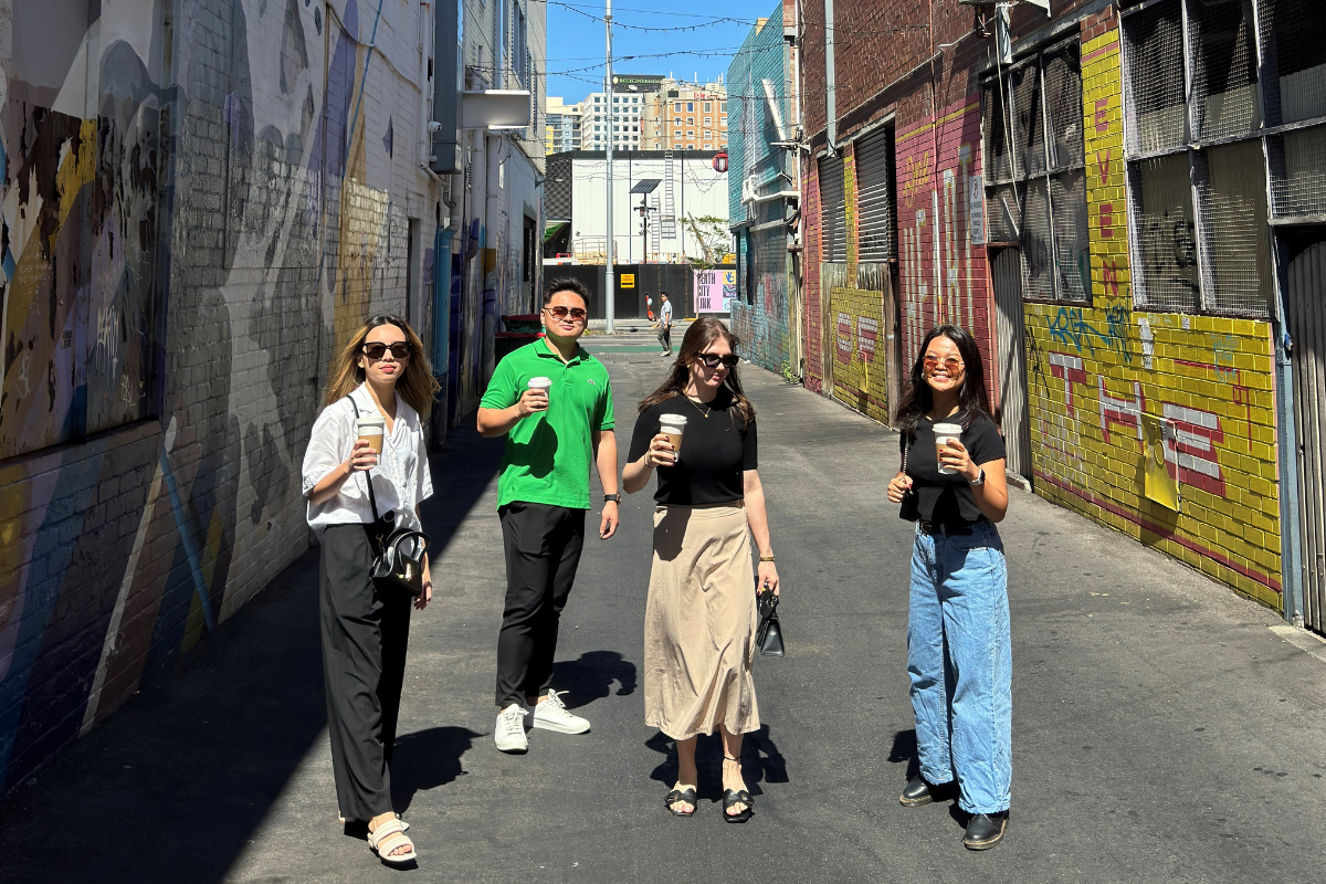International students holding their coffee cups in a laneway 