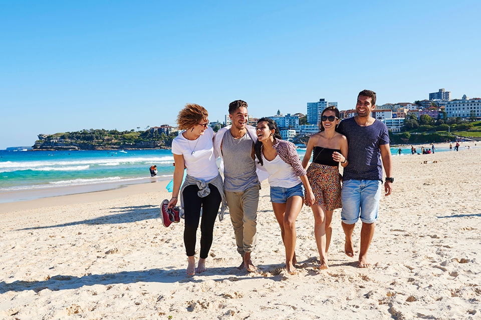 Group of students walking together on Bondi Beach. 