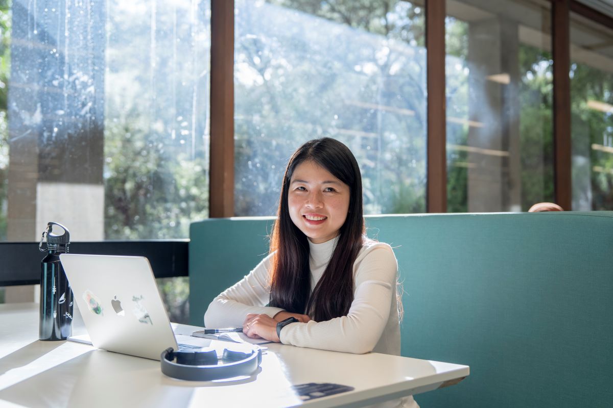 A student sitting with her laptop smiling at the camera