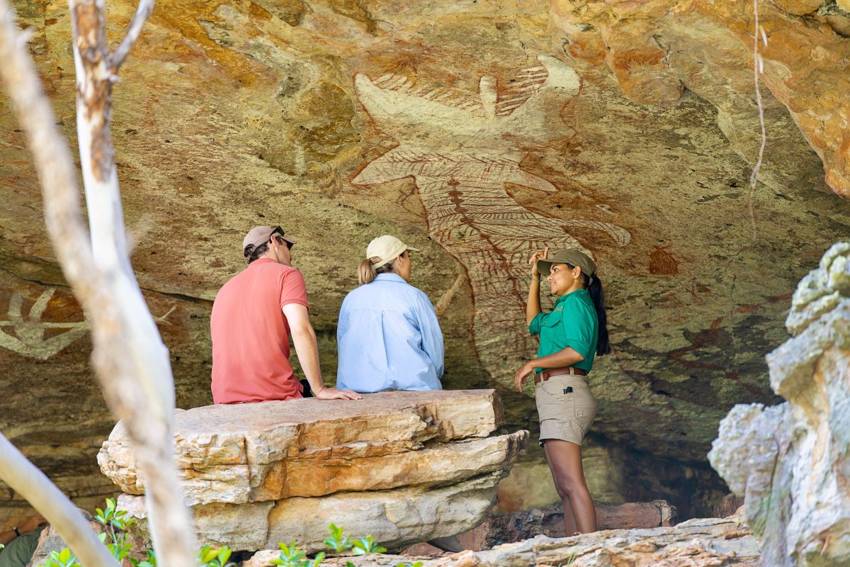 Two people learning about Aboriginal rock art from a guide. Credit Tourism Australia