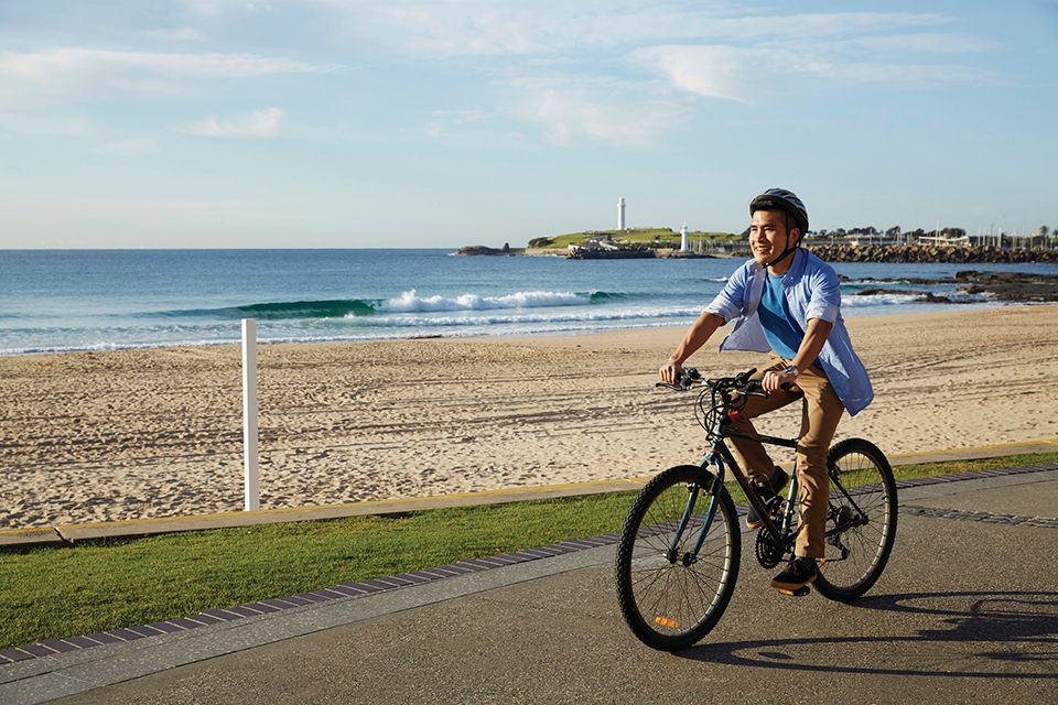 Man riding a bike along Wollongong Beach.