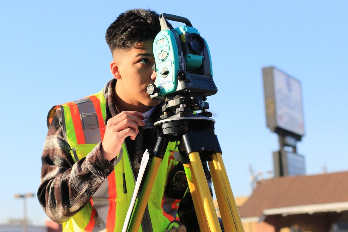 A student looks through a laser level on a building site.