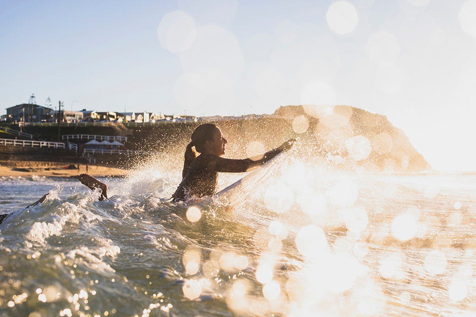 Surfer paddling out at sunrise at Bar Beach, Newcastle.  