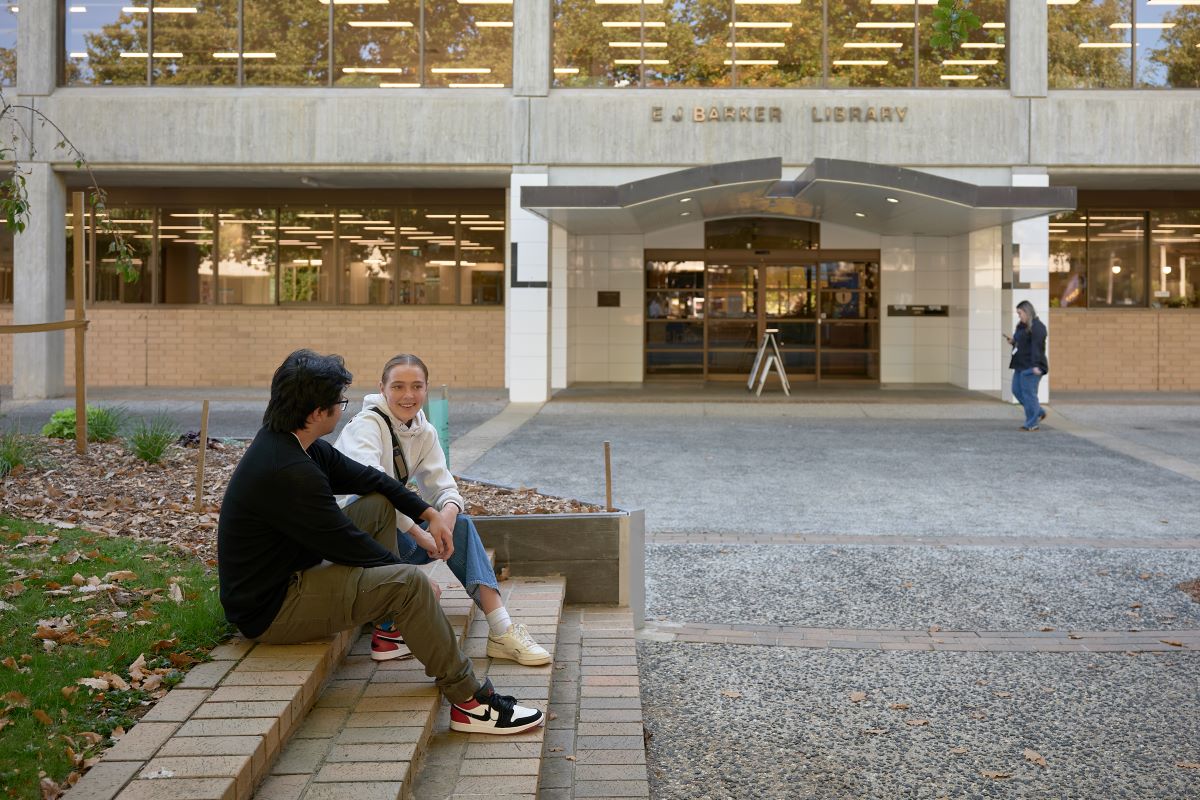 Two students sitting out the front of their campus library