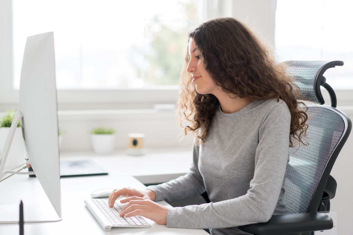 A student sitting at a desk, typing on a computer