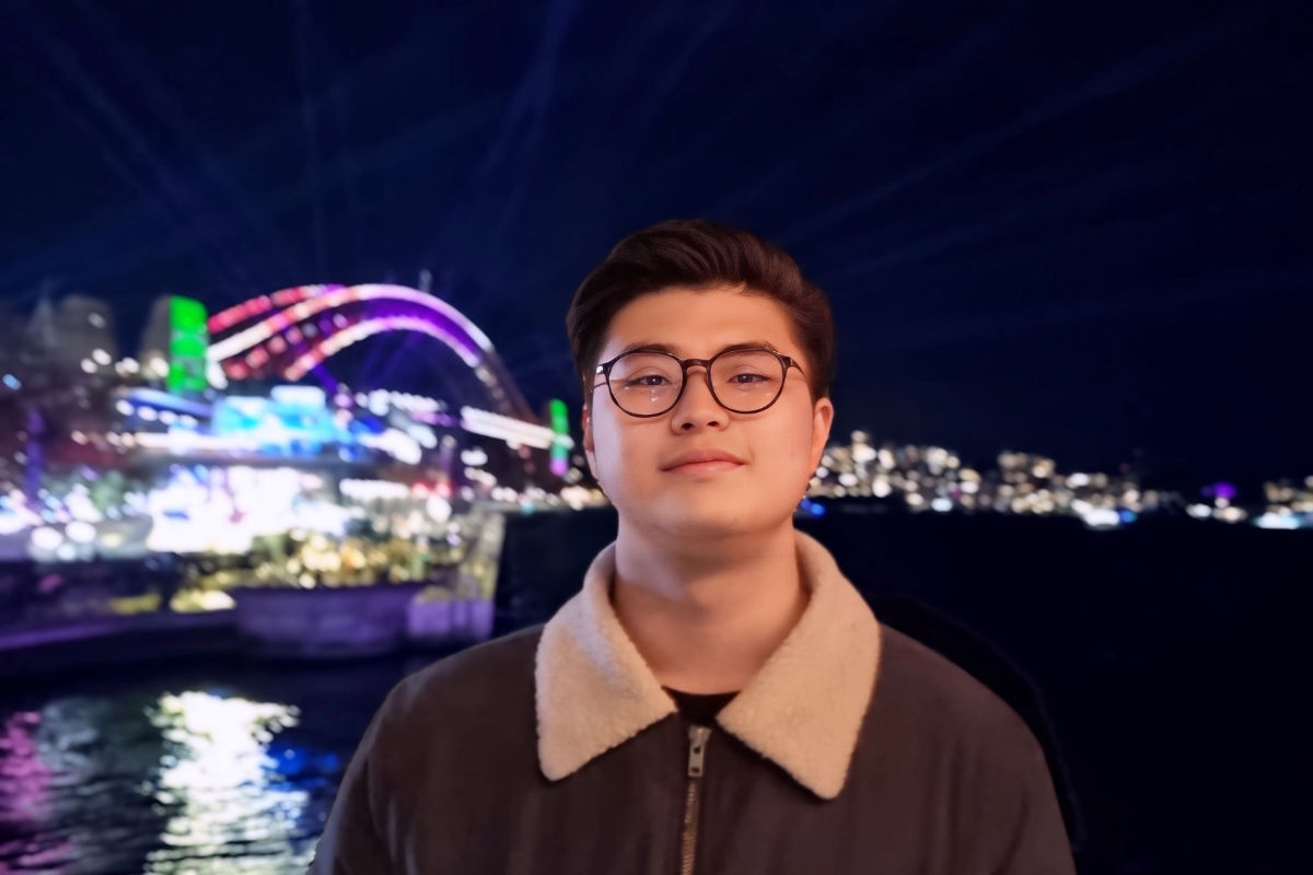 International student, Axel, in front of the Sydney Harbour bridge lit up at night