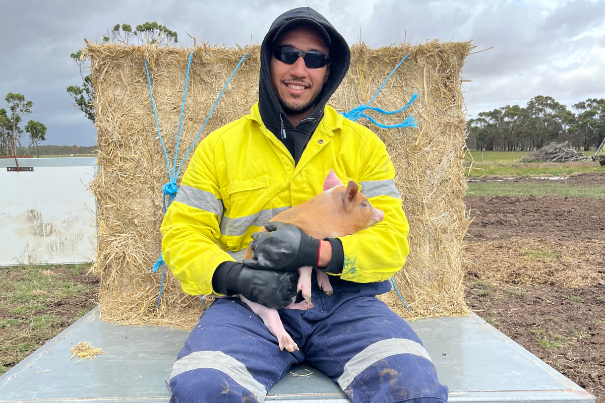 International student, Roy, holding a piglet 