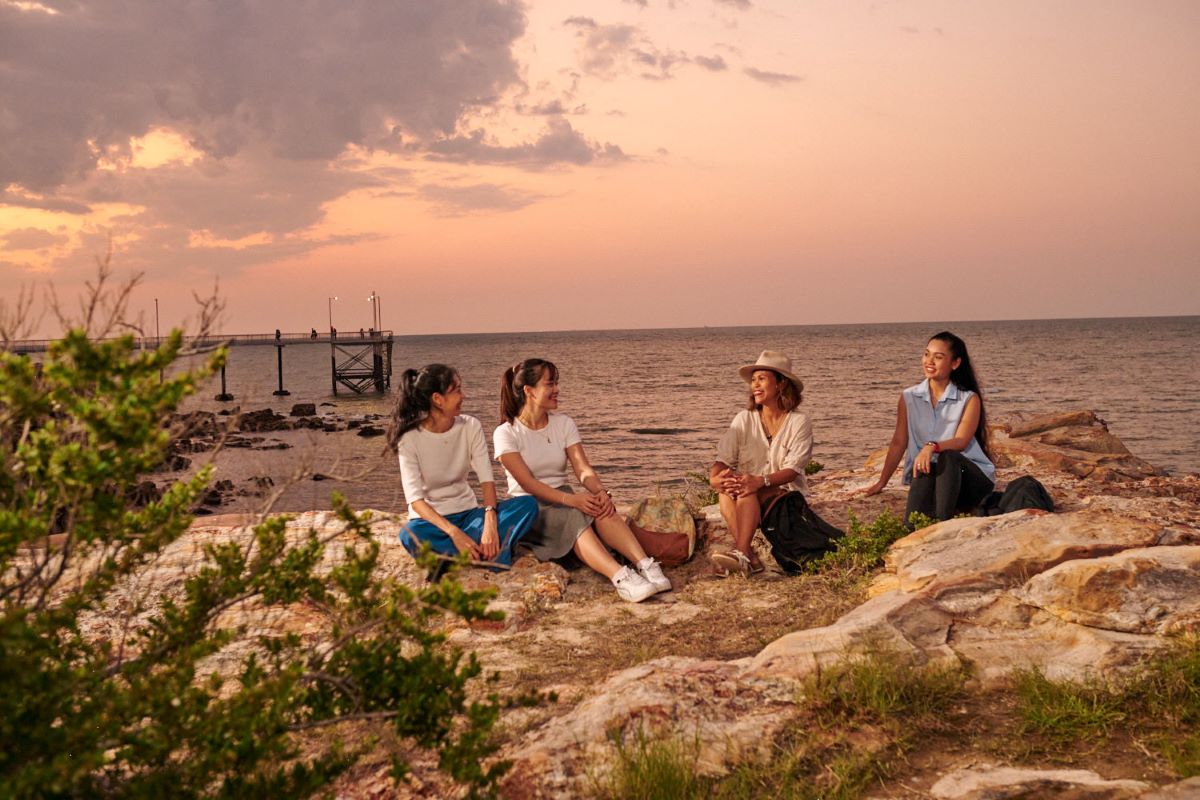 International students from Vietnam and the Philippines socialising on the rocks at Nightcliff Beach, Darwin at sunset.