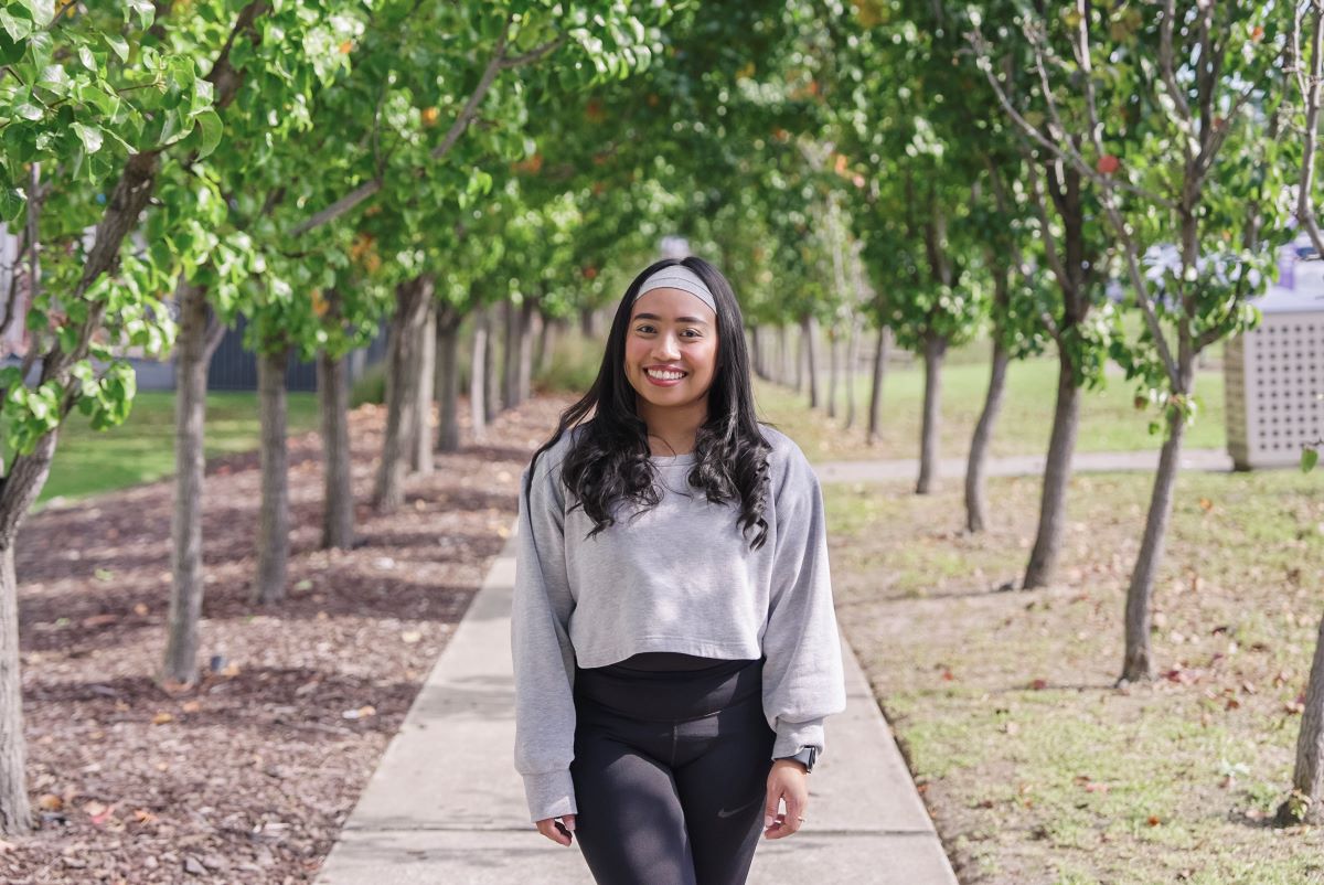 International student, Jade, standing on a path in a park smiling