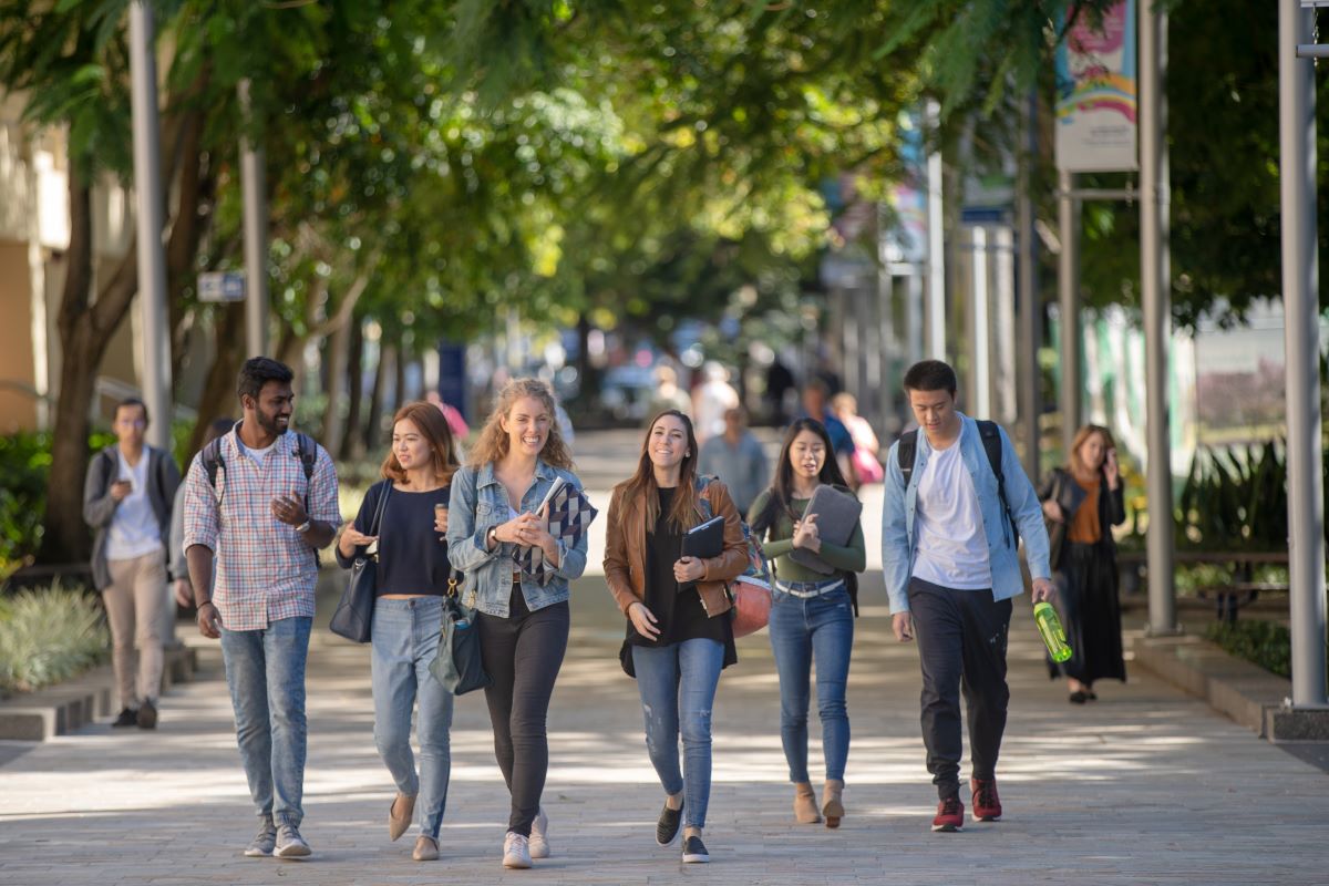 A group of international students walking down a sidewalk on campus in Australia.