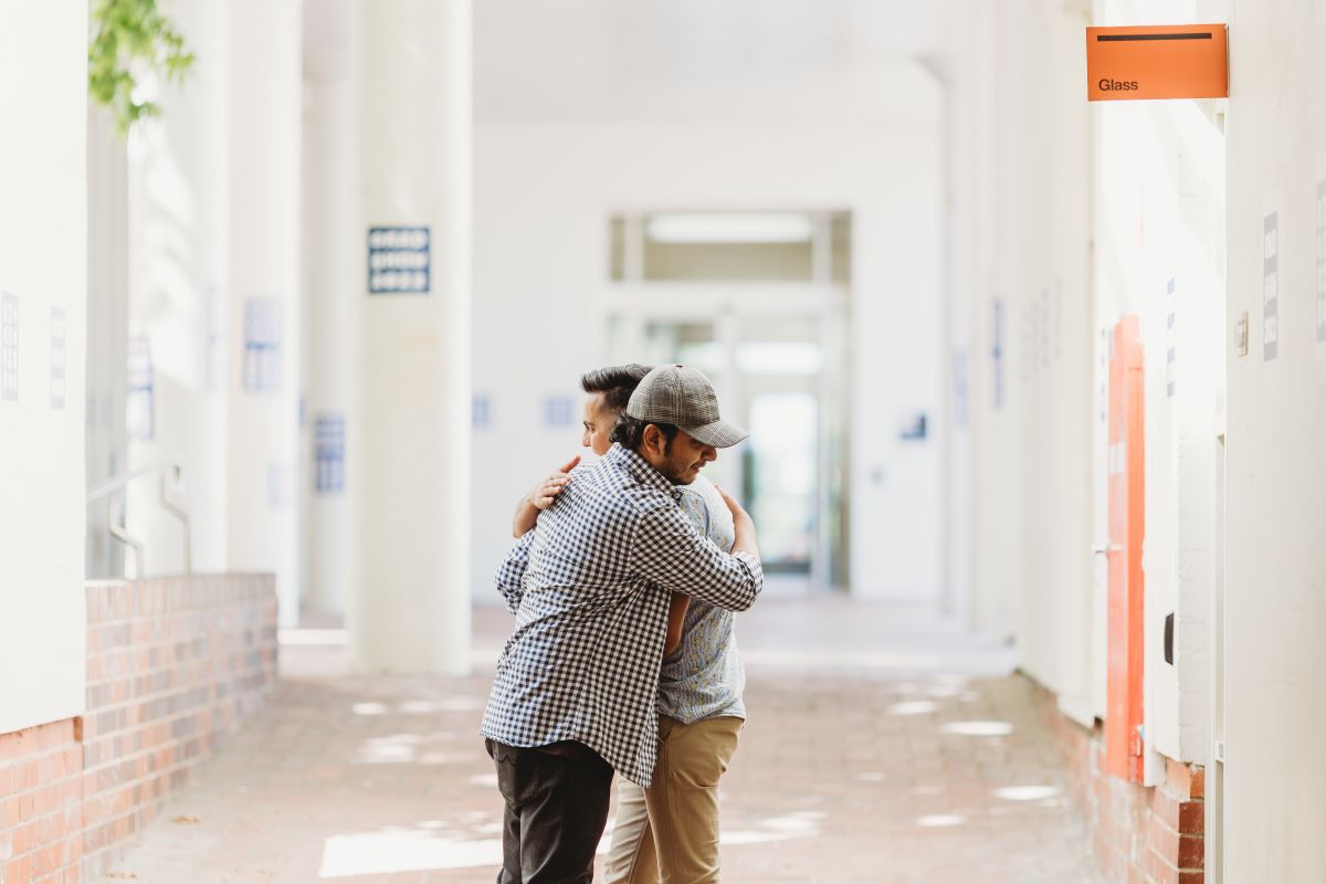 Two male international students hugging goodbye