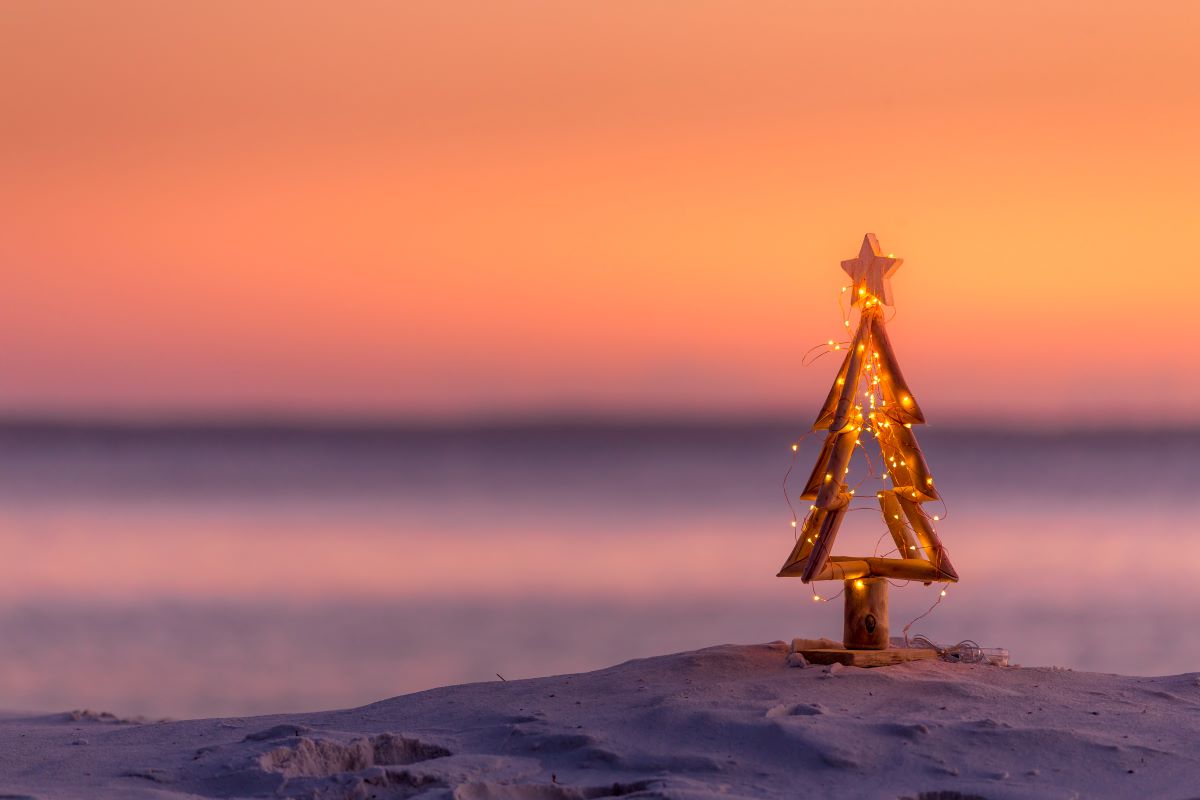 A small Christmas tree ornament on the beach at sunset
