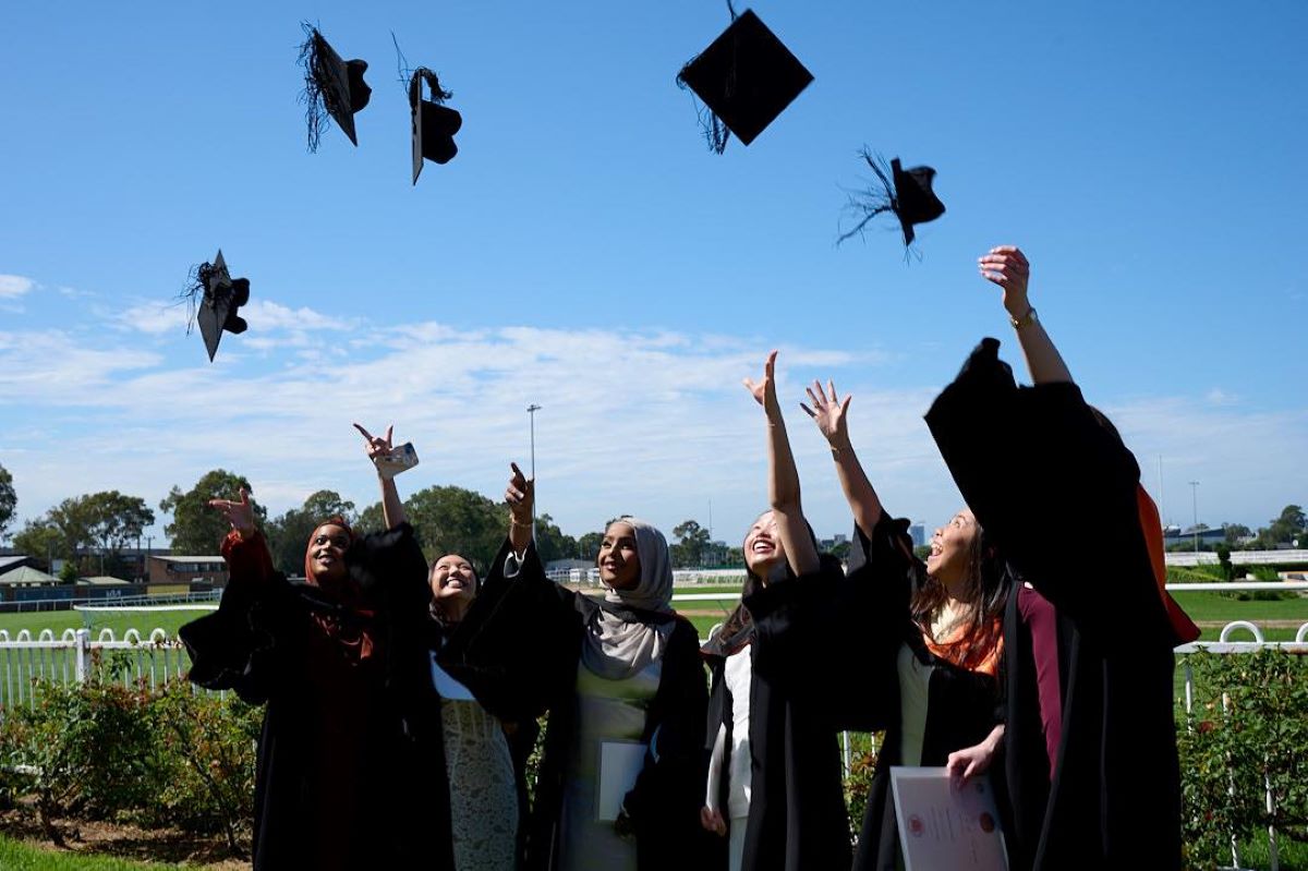 A group of ACU graduates throwing their hats in the air