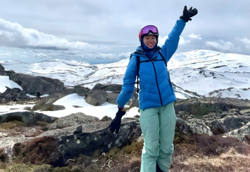 International student, Greene, standing in ski gear with a snowy mountain behind her