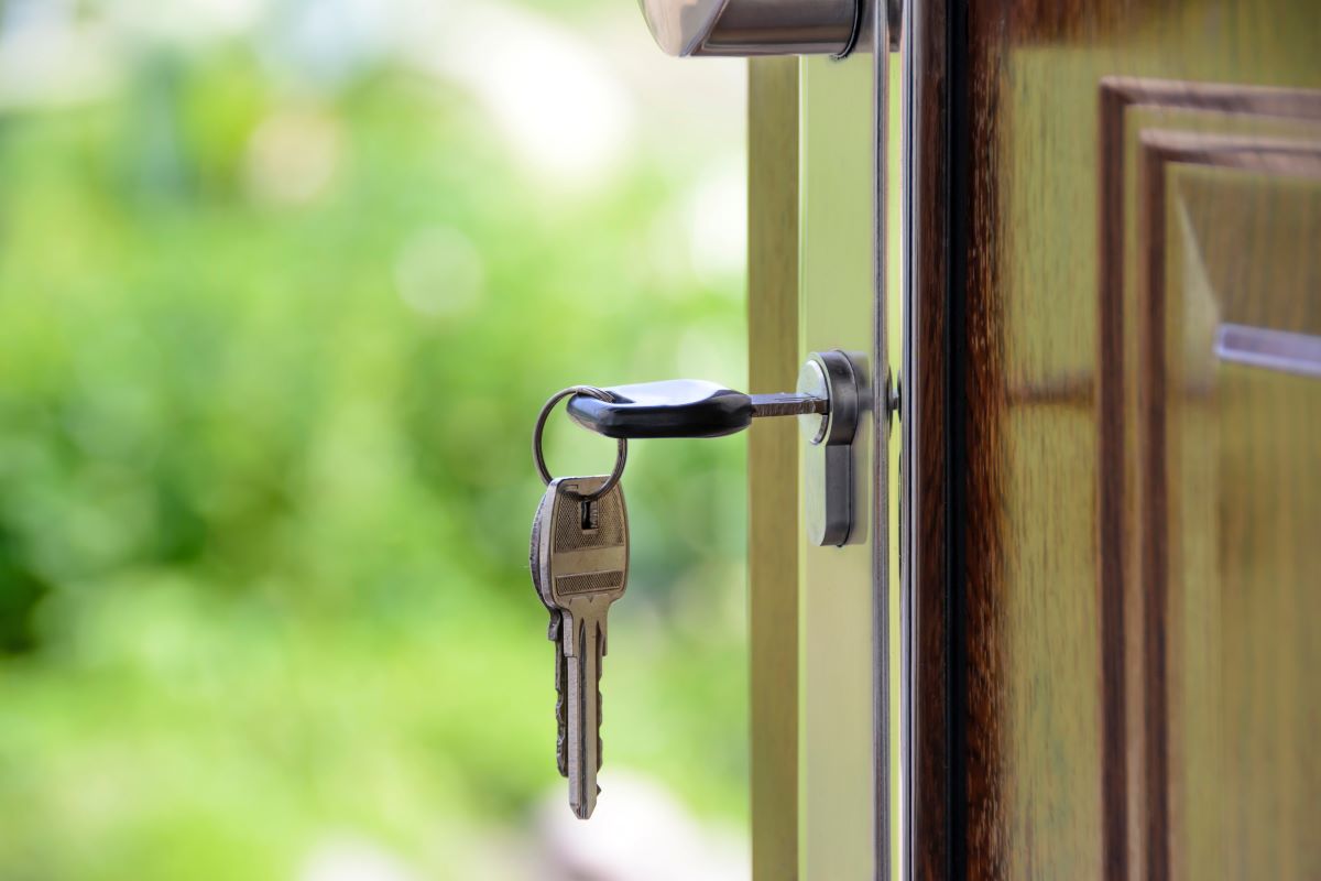 A set of keys hang from the lock of an open front door. 