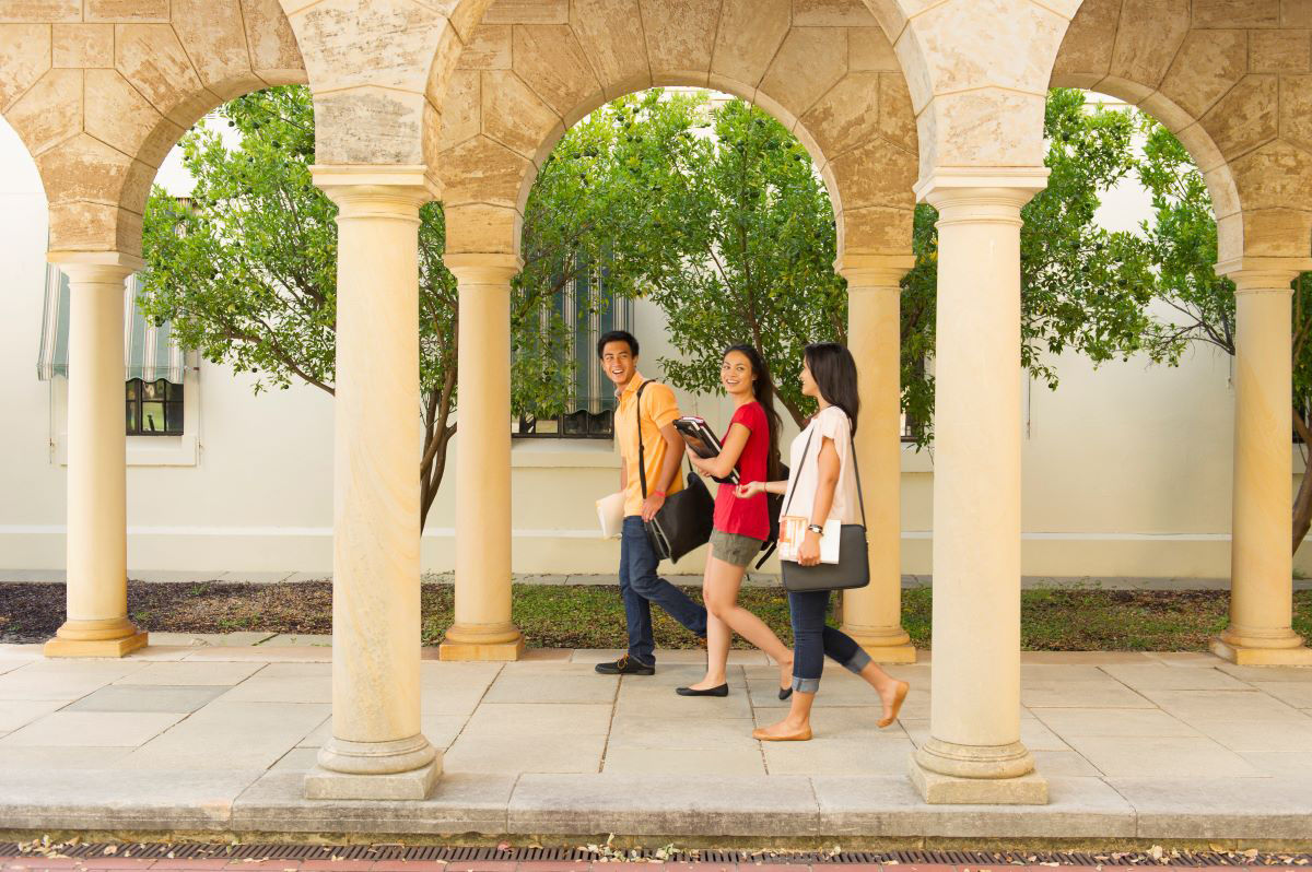 Three international students walk through a university campus