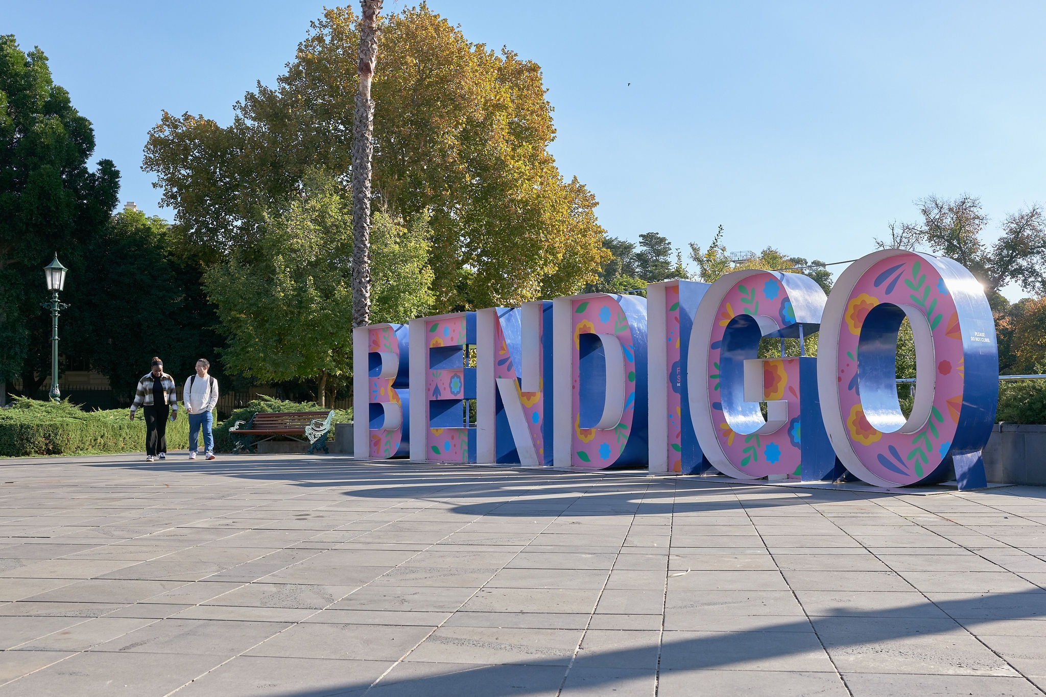 Two students walking next to a big sign that says "Bendigo"
