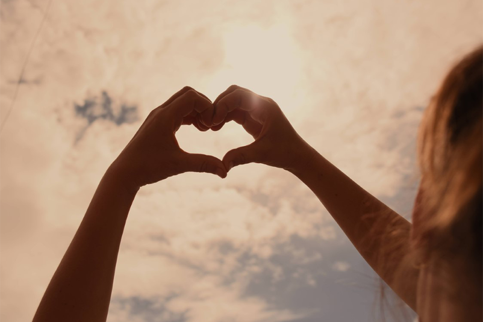 a woman making a heart shape with her hands.    