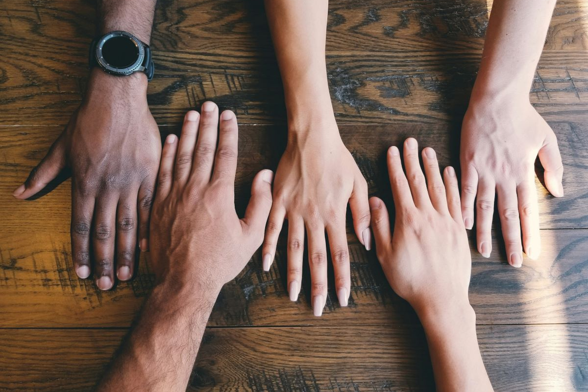 Hands of different colours on a table side by side.
