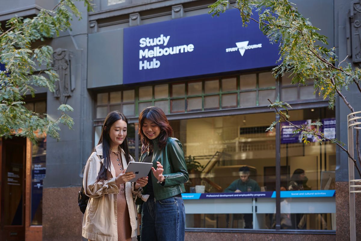 Two students looking at an iPad out the front of the Study Melbourbe Hub