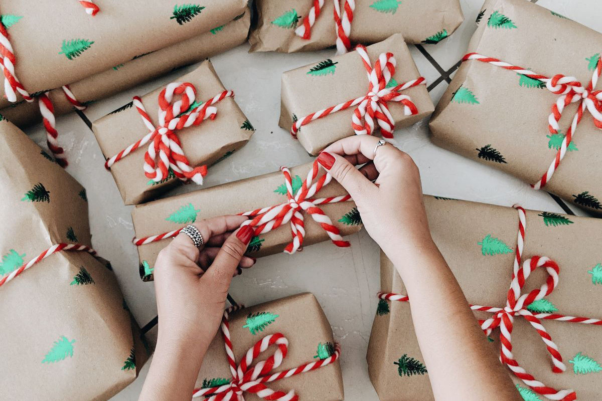 A pile of Christmas presents wrapped in brown paper and red and white string